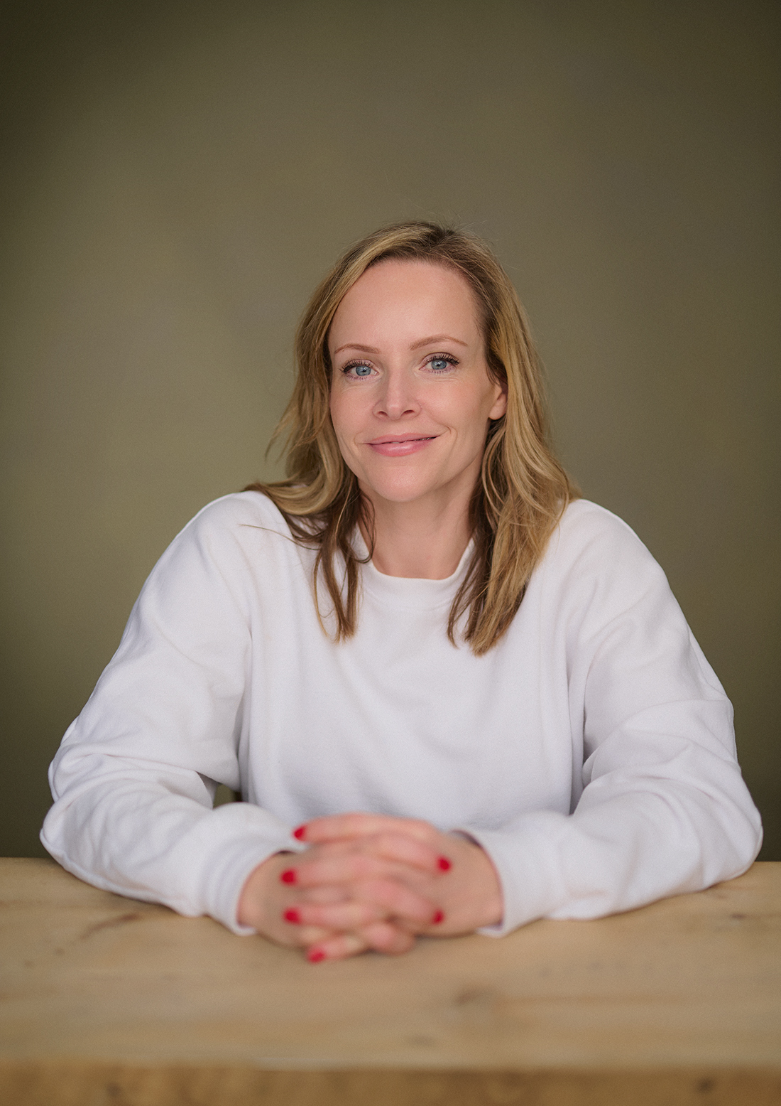 Author portrait of Becky Mayhew seated in a London studio with a green canvas backdrop