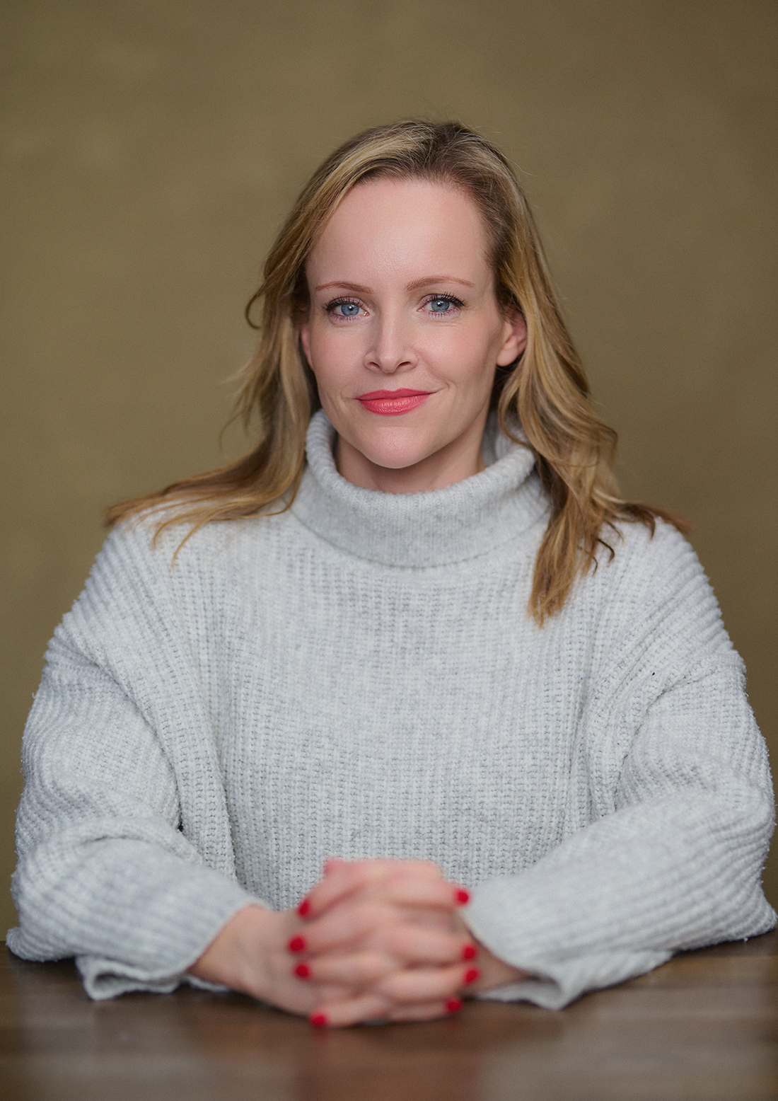 Author portrait of Becky Mayhew seated in a London studio with a light pink canvas backdrop