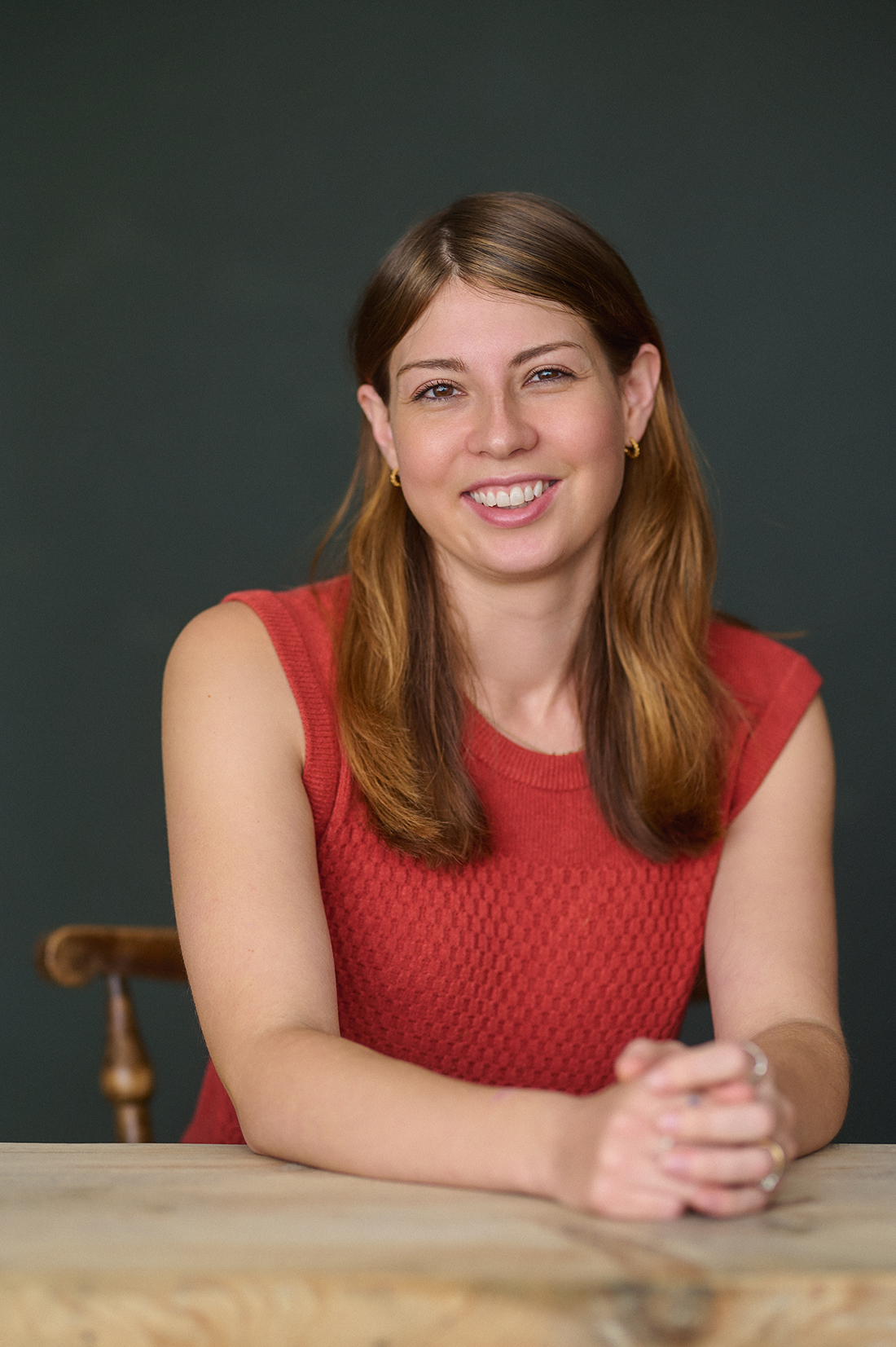 Author portrait of Hetta Howes seated at a table with a dark Abyss backdrop, London studio