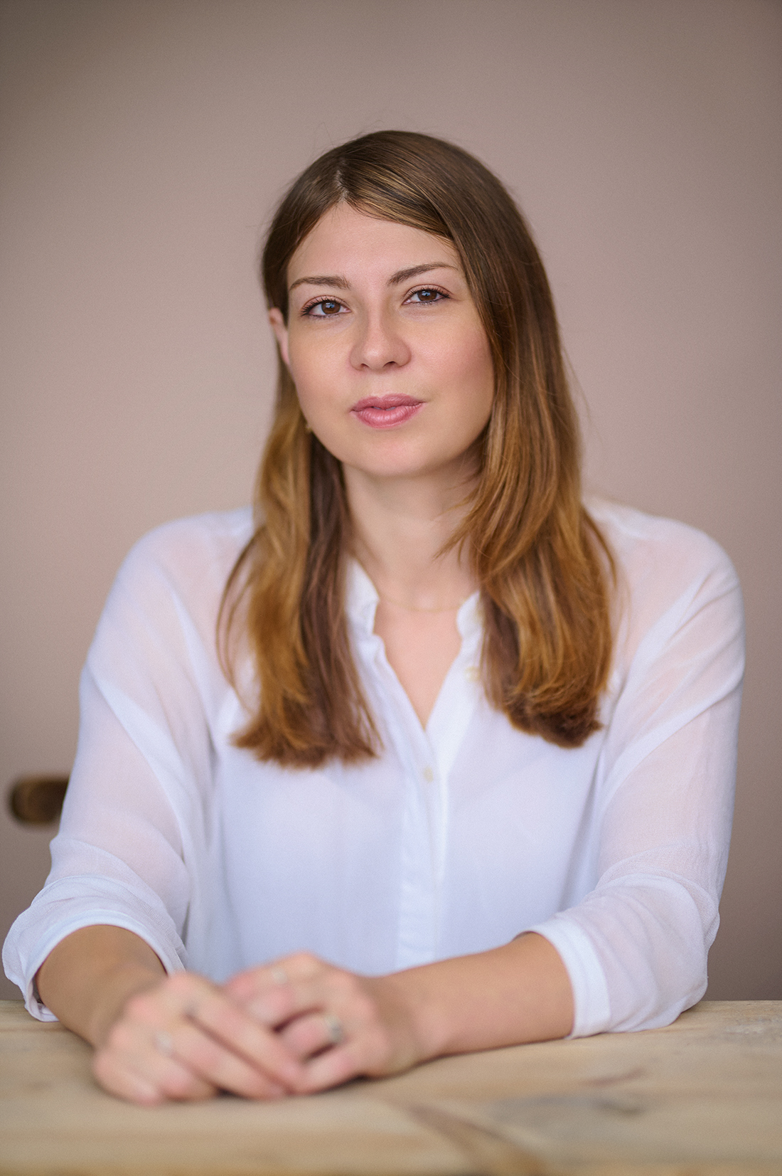 Author portrait of Hetta Howes seated at a table with a light pink backdrop, London studio