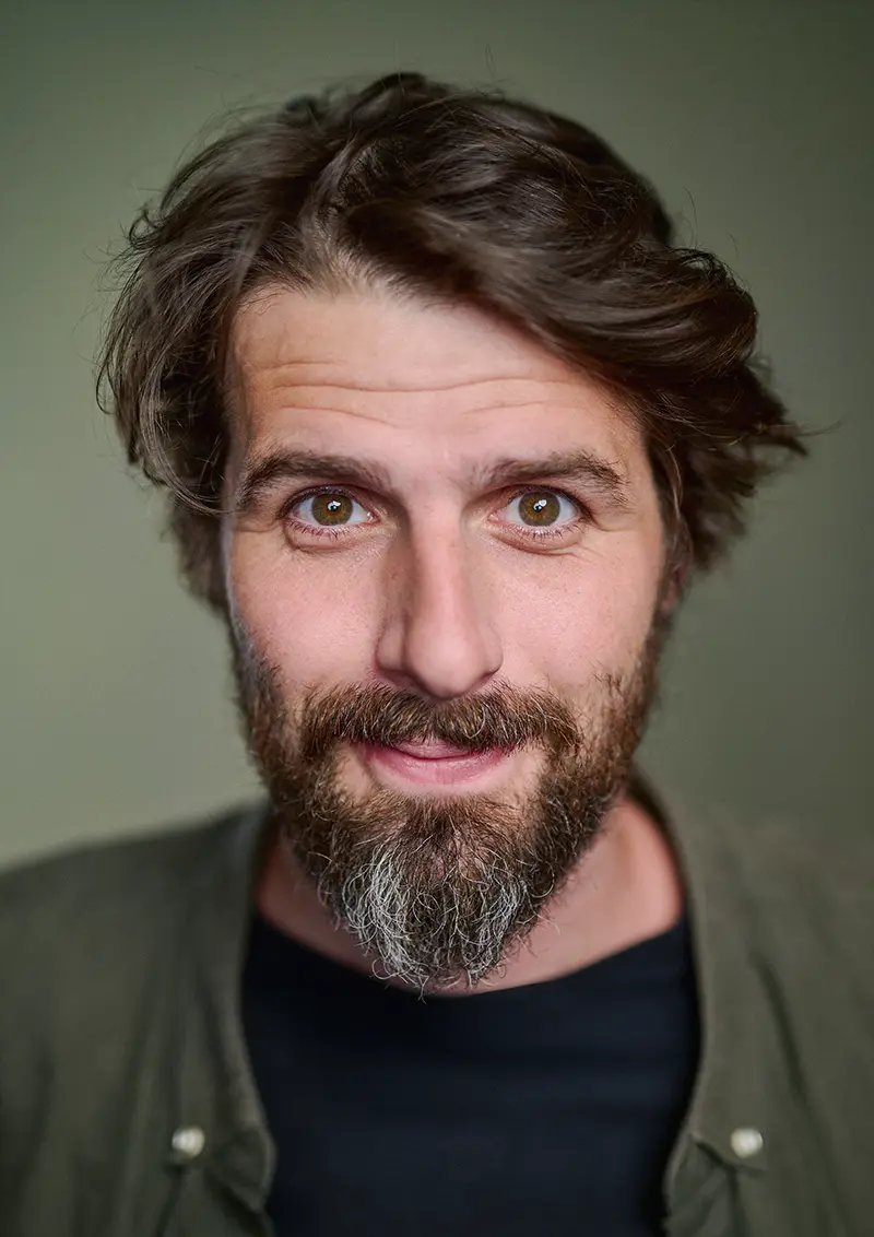 Actor headshot of Henri in studio with professional lighting and a green canvas backdrop