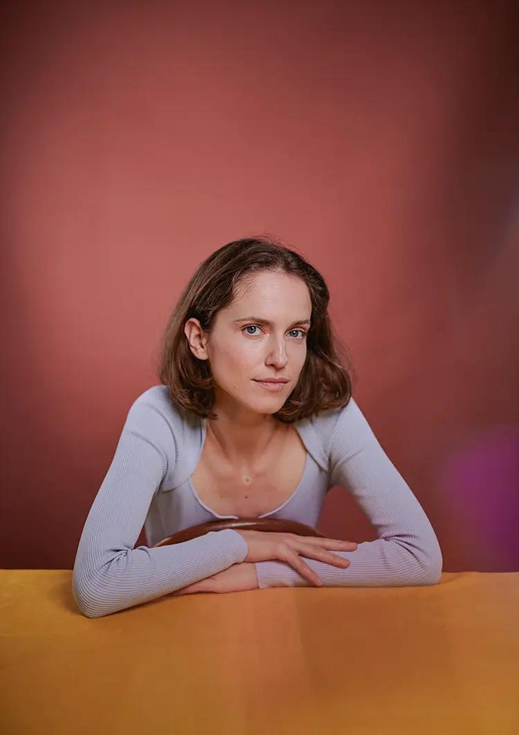 Artistic actor portrait of Iva in London with terracotta backdrop and yellow table