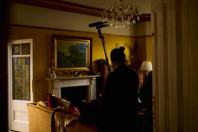Boom operator recording sound in a period living room during filming