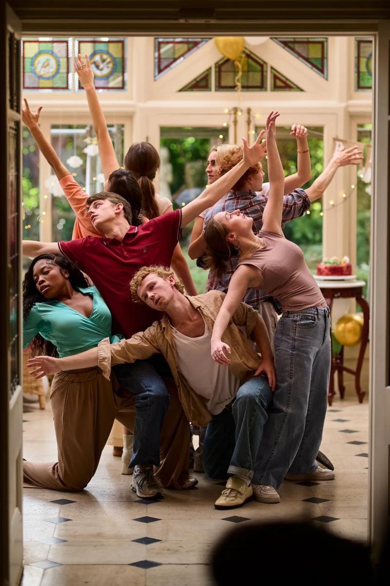 Cast of a short film holding a choreographed pose in a conservatory during filming