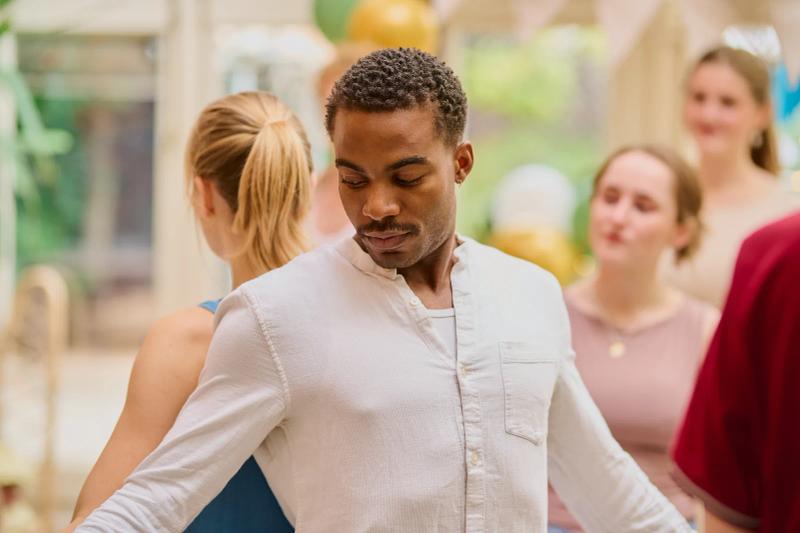 Actor performing a dance scene with the rest of the cast behind him