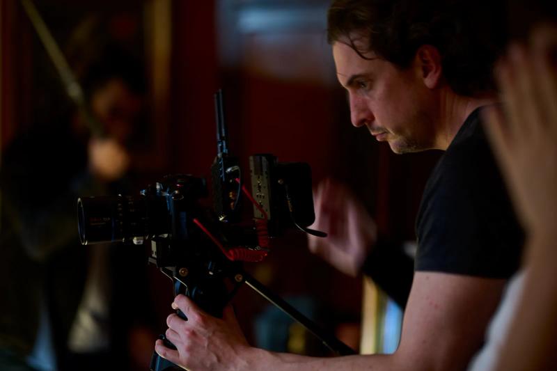 Camera operator framing a shot on a rigged cinema camera during filming