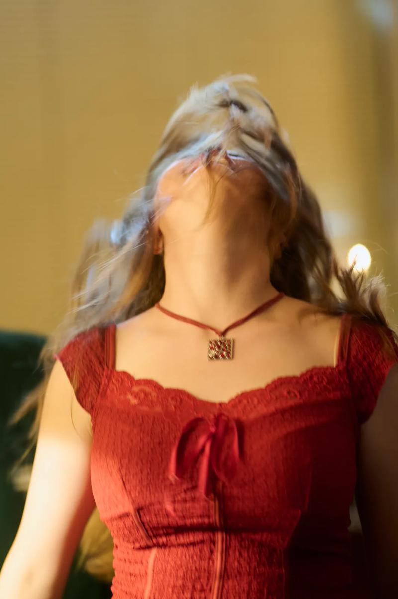 Actress mid-turn in a red dress during a dance scene, her hair caught in motion