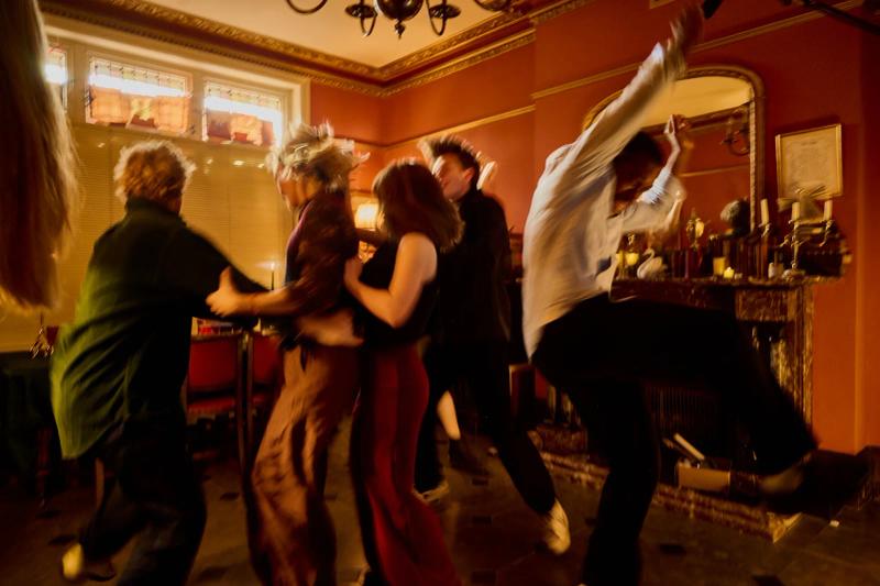 Cast filming a party scene in a candlelit living room