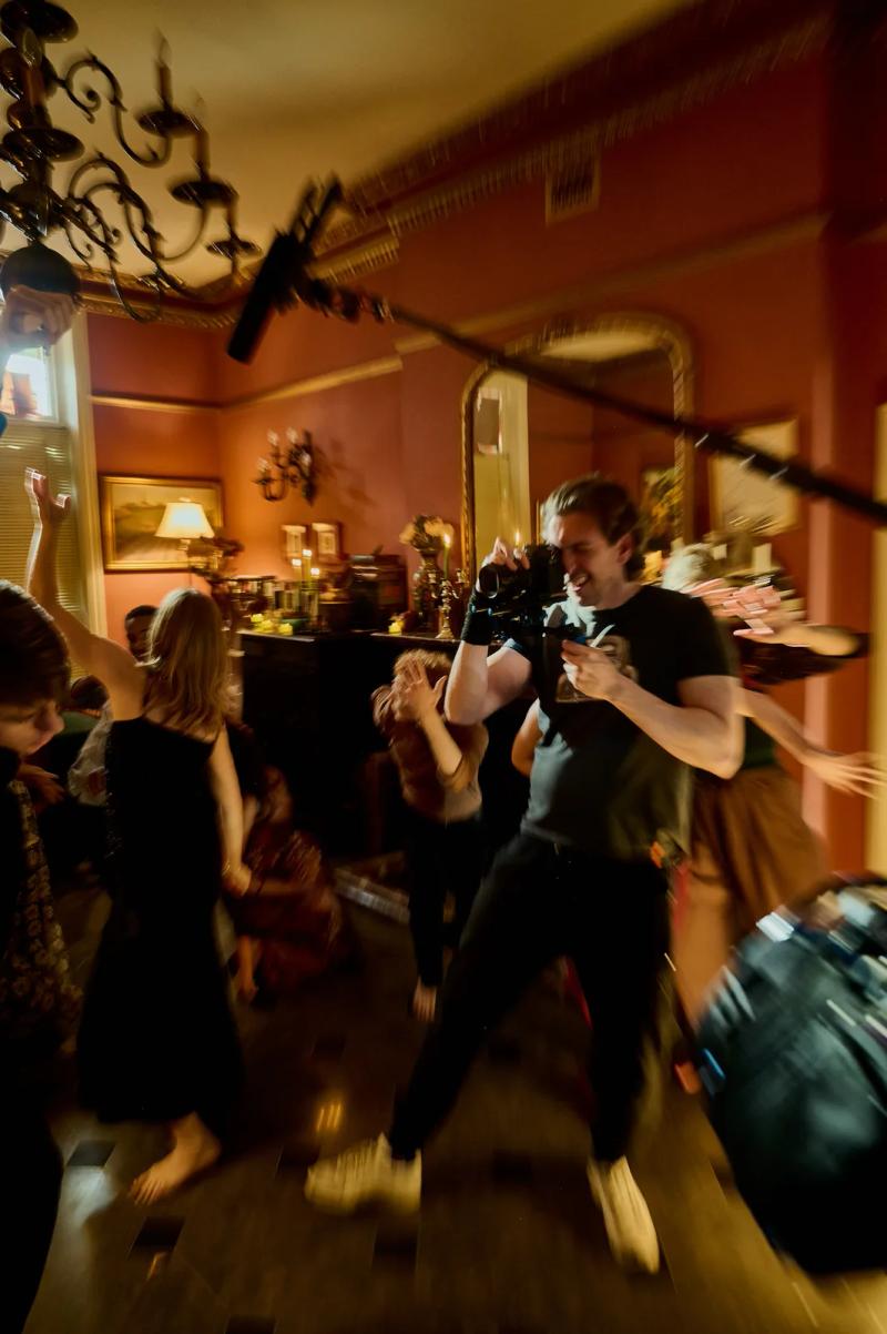 Camera operator filming from the middle of a dance scene as the cast moves around him