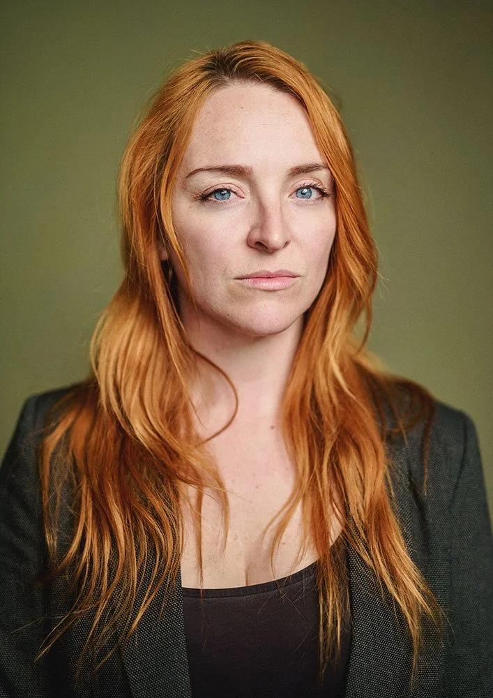 Headshot of red haired actress with intense stare in my studio with a green canvas backdrop.