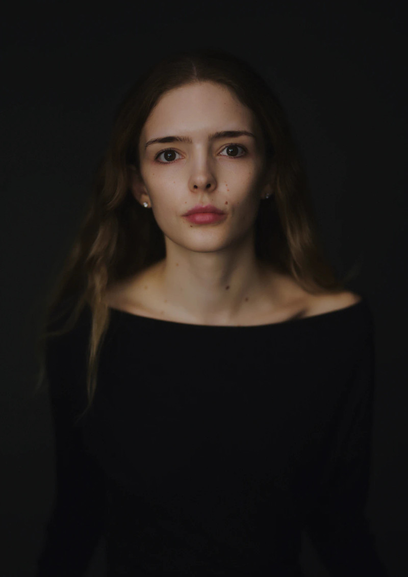 Low-key model portfolio portrait of Lauren in a black off-the-shoulder top, against a dark backdrop in my London studio.